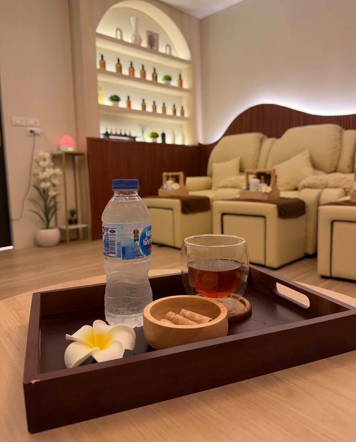 Hot bael fruit tea, water and thong muan, rolled Thai coconut snacks, on a wooden tray in the foot massage area